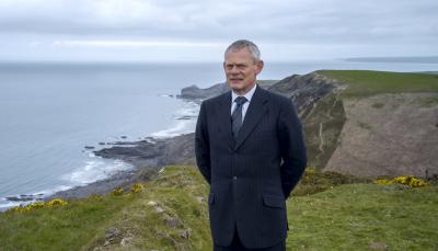 Martin Clunes as the titular 'Doc Martin' stand on a clifftop in the Season 8 key art